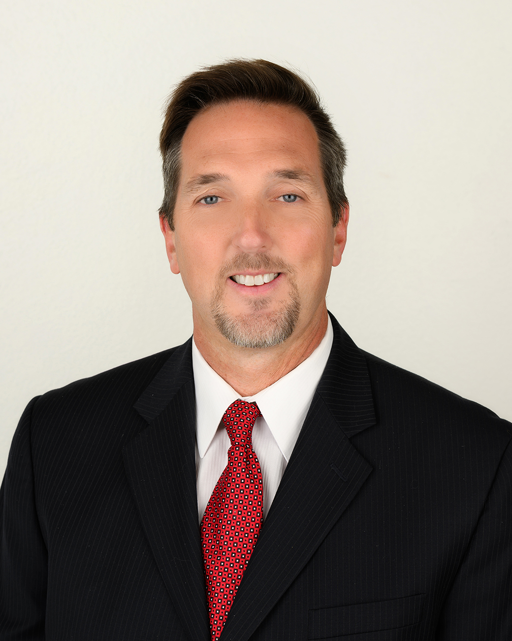 NWIA HS Erik Hoak Man smiling with black suit coat and red tie
