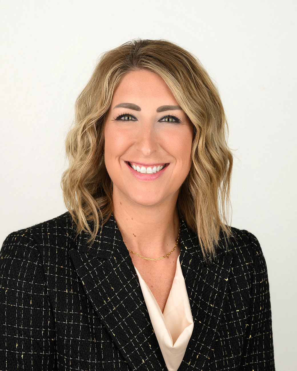Woman smiling in black jacket with cream top