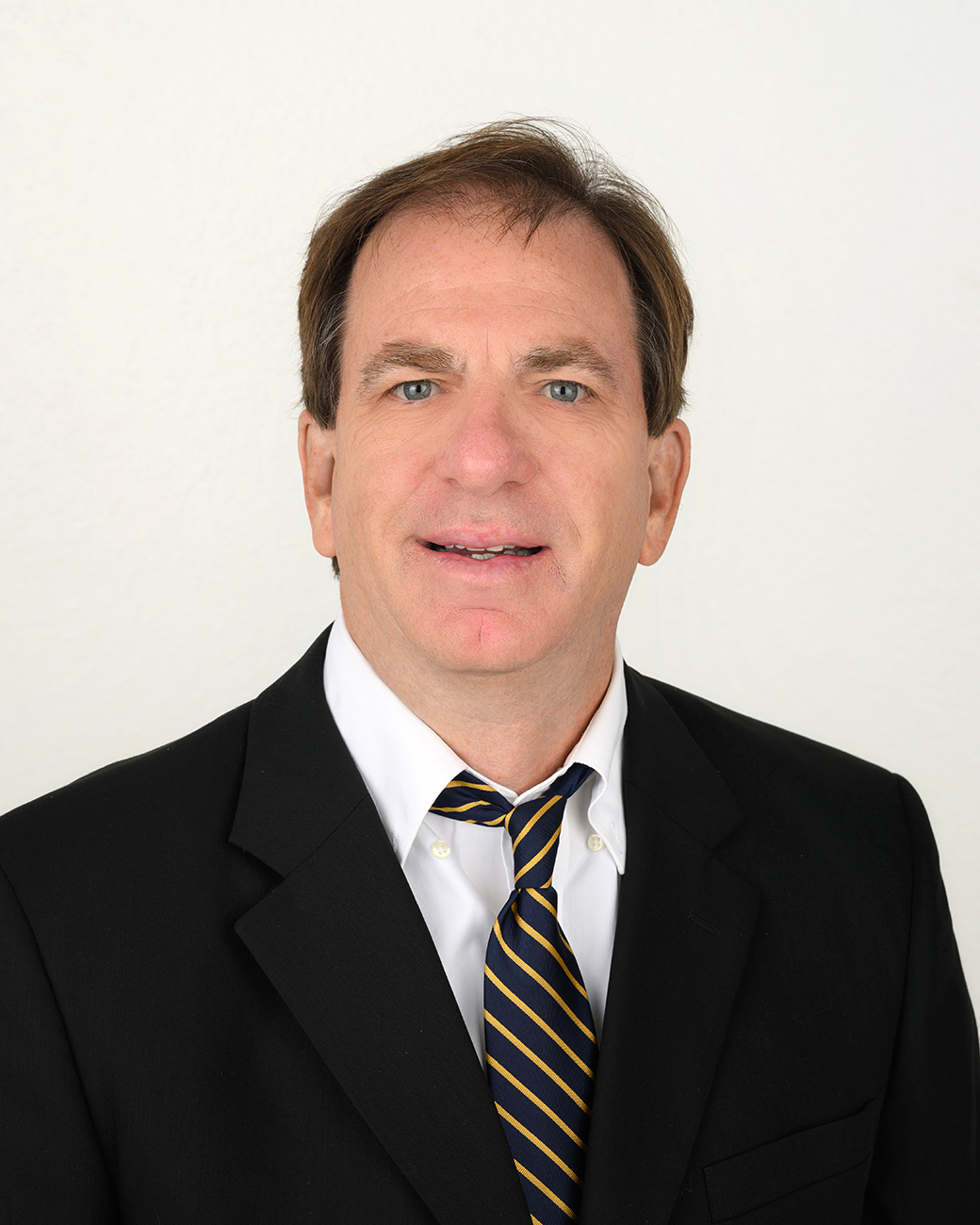 Man smiling in professional suit, black jacket with white shirt and stripe tie